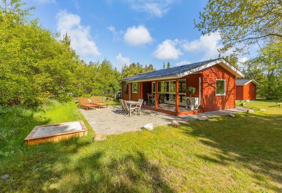 Klassisches rotes Holzferienhaus mit eigener Feuerstelle in Houstrups grüner Natur
